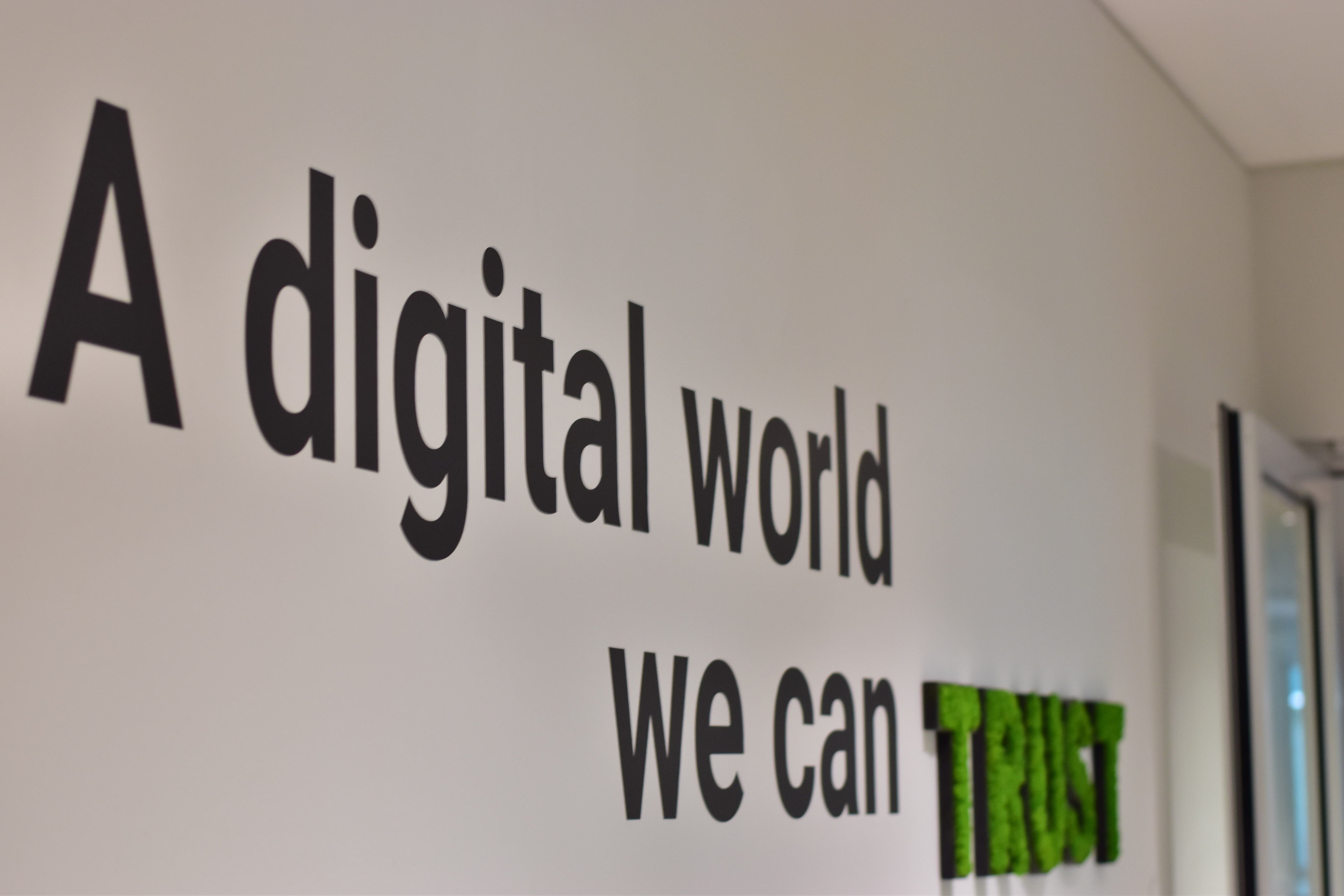 Een foto uit het kantoor van Trusted Shops met de slogan "A digital world you can trust" aan de muur.